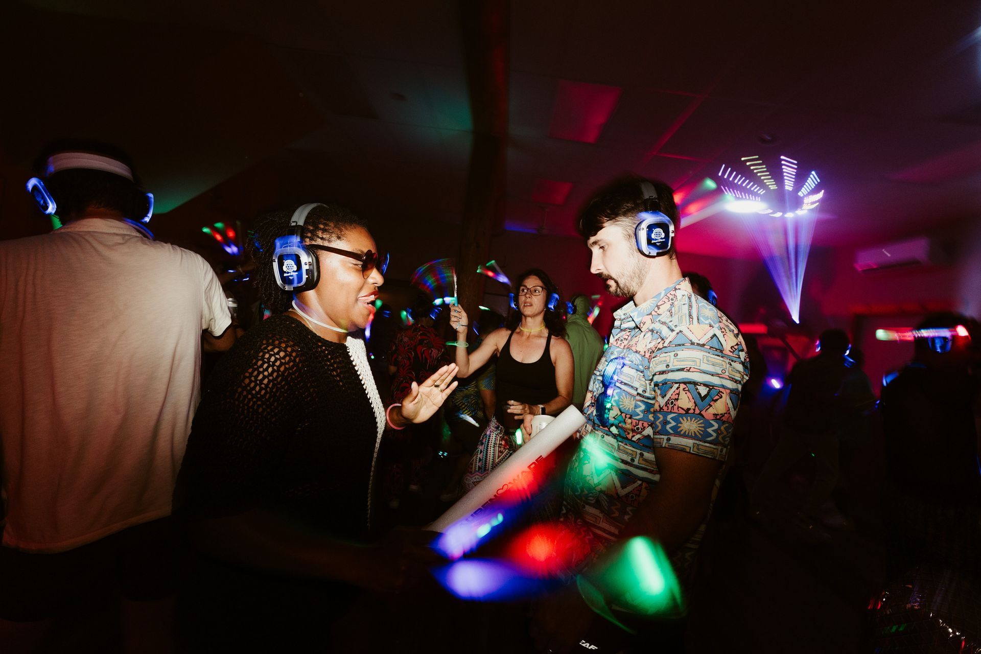 A group of people wearing headphones are dancing at a party.
