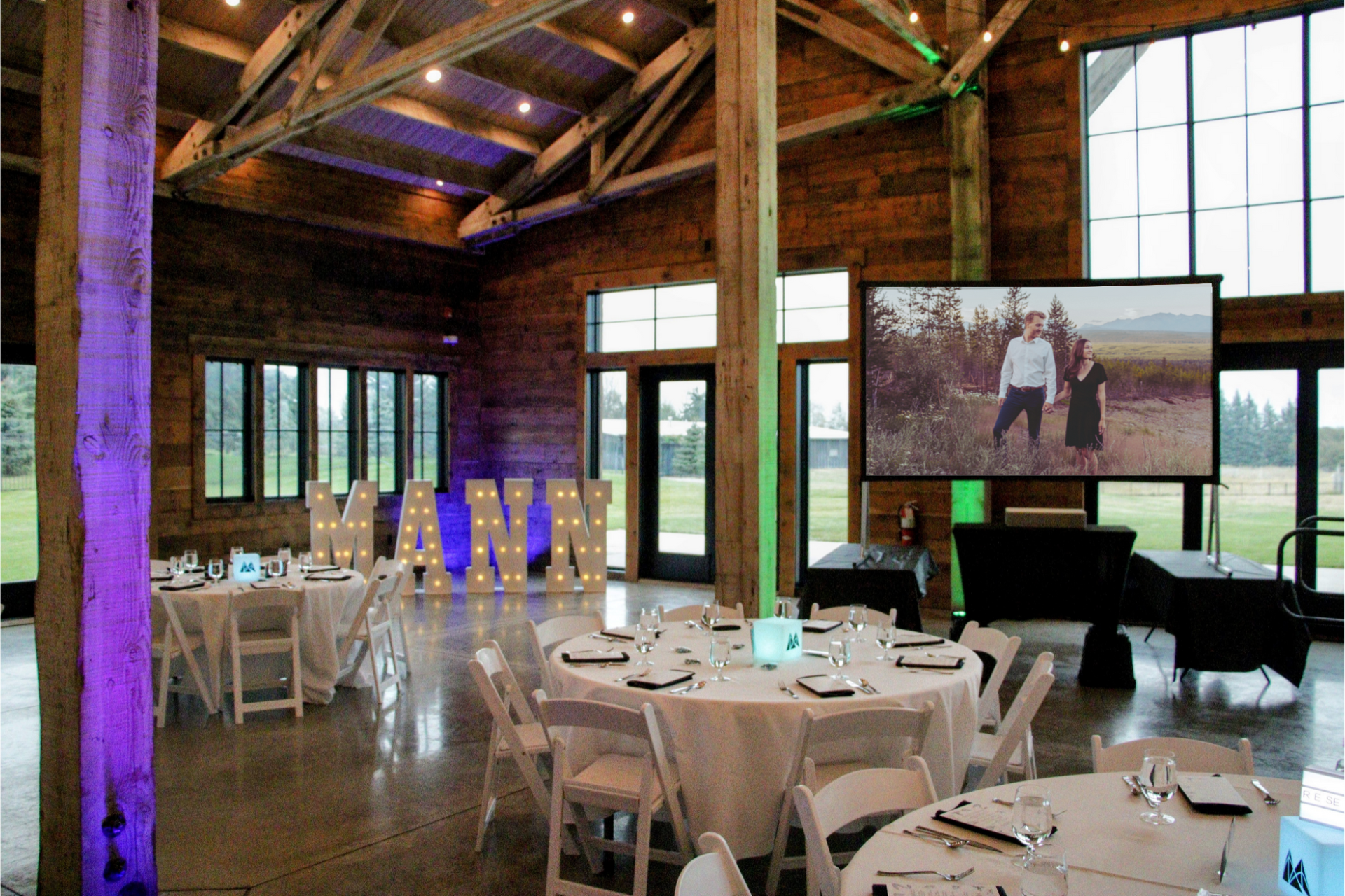 A large room with tables and chairs set up for a wedding reception.