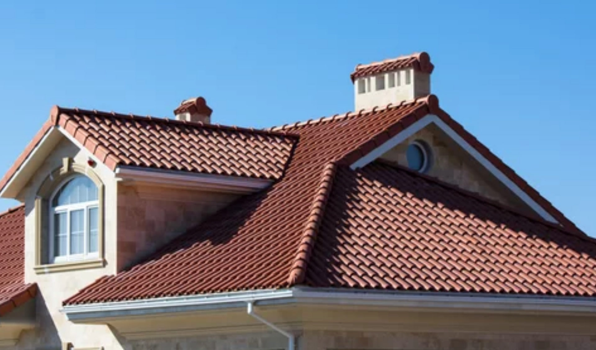 AD Construction NJ - Red tile roof on a beige house against a clear blue sky.