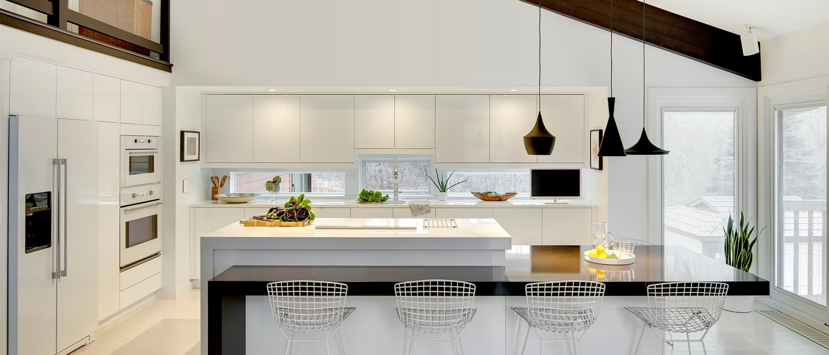 AD Construction NJ - Modern white kitchen with a black countertop island and hanging black pendant lights.