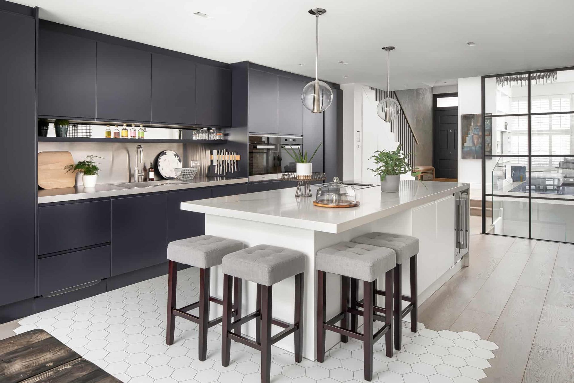 AD Construction NJ - Modern kitchen with dark blue cabinets, white island, and gray stools.