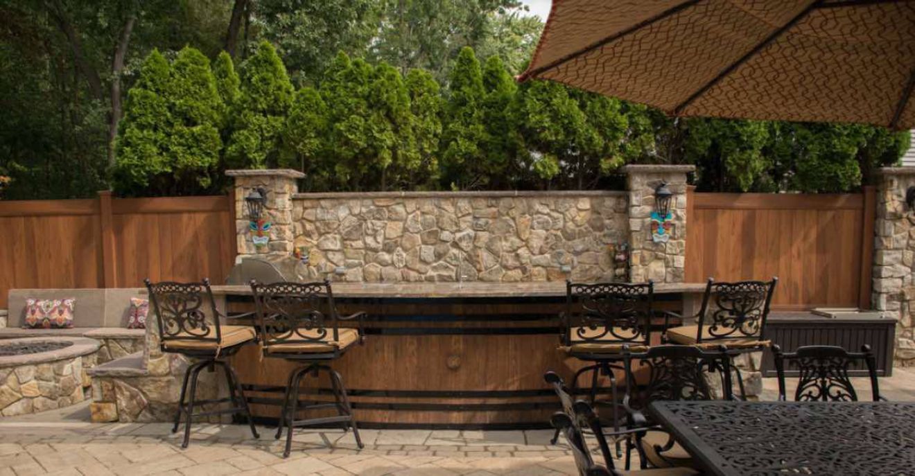 AD Construction NJ - Outdoor bar area with stone and wood features, chairs, and an umbrella.