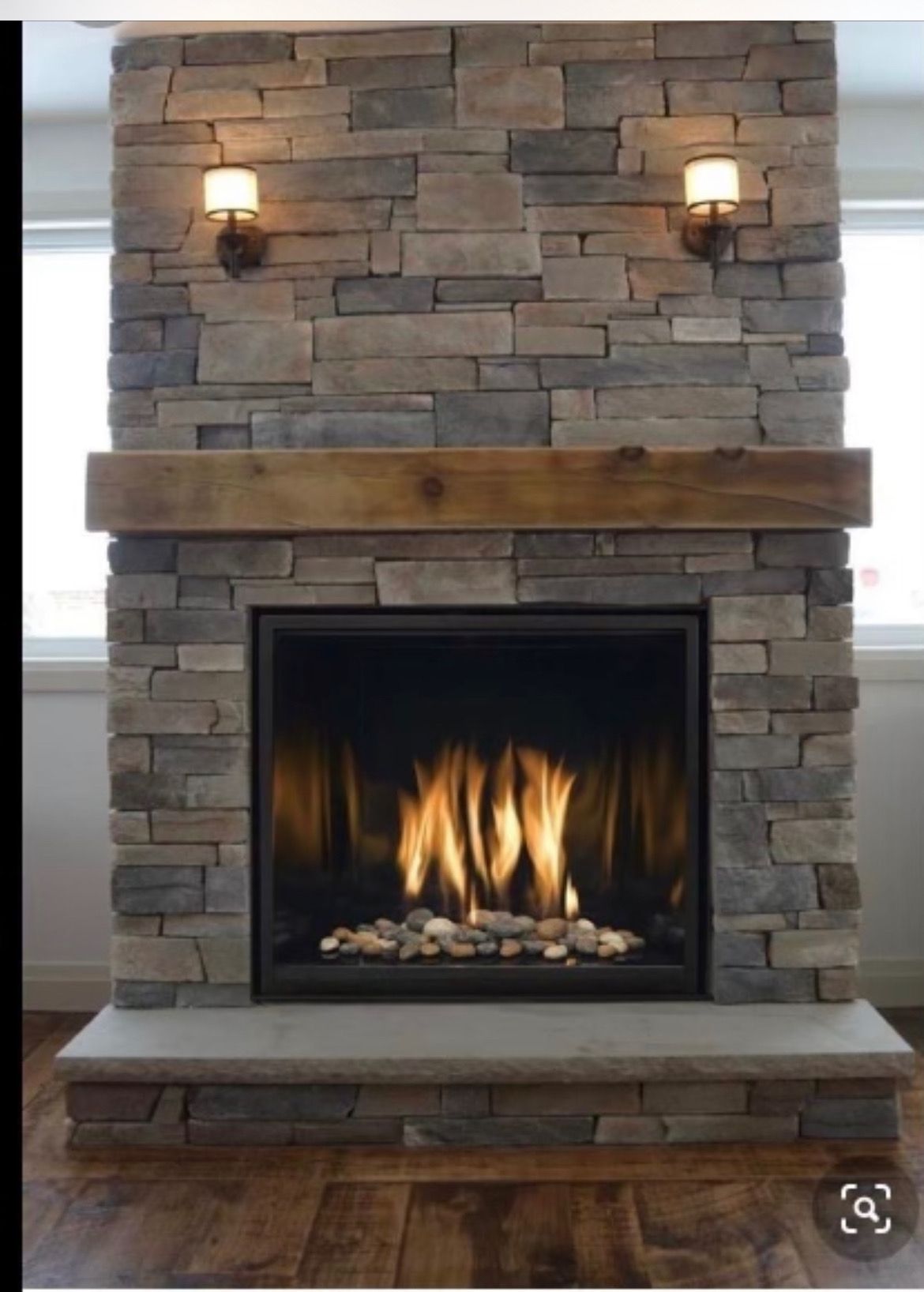AD Construction NJ - Stone fireplace with flames, wooden mantel, sconces, and stone hearth.