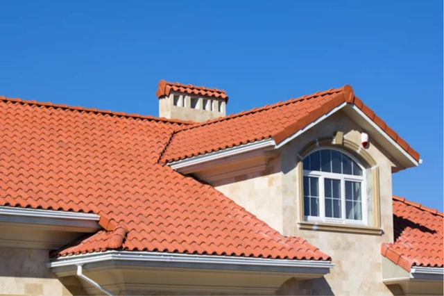 AD Construction NJ - Red tile roof with chimney and dormer window against a blue sky.