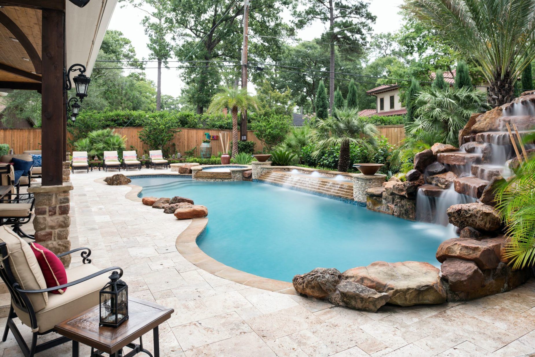 AD Construction NJ - A luxurious backyard with a pool, waterfall, and patio seating.