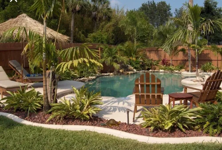 AD Construction NJ - Backyard pool with tiki hut, lounge chairs, tropical plants, and wooden chairs.