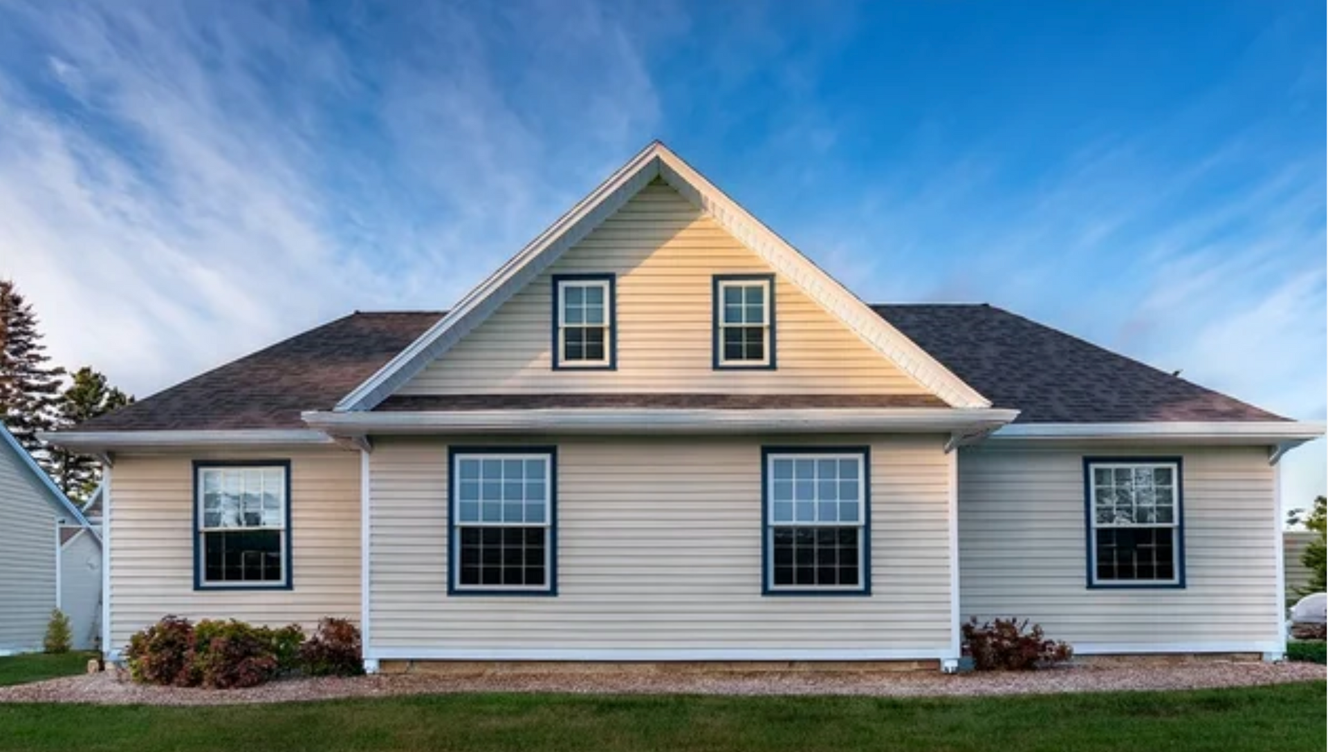 AD Construction NJ - Beige house with gabled roof, multiple windows, and blue sky.