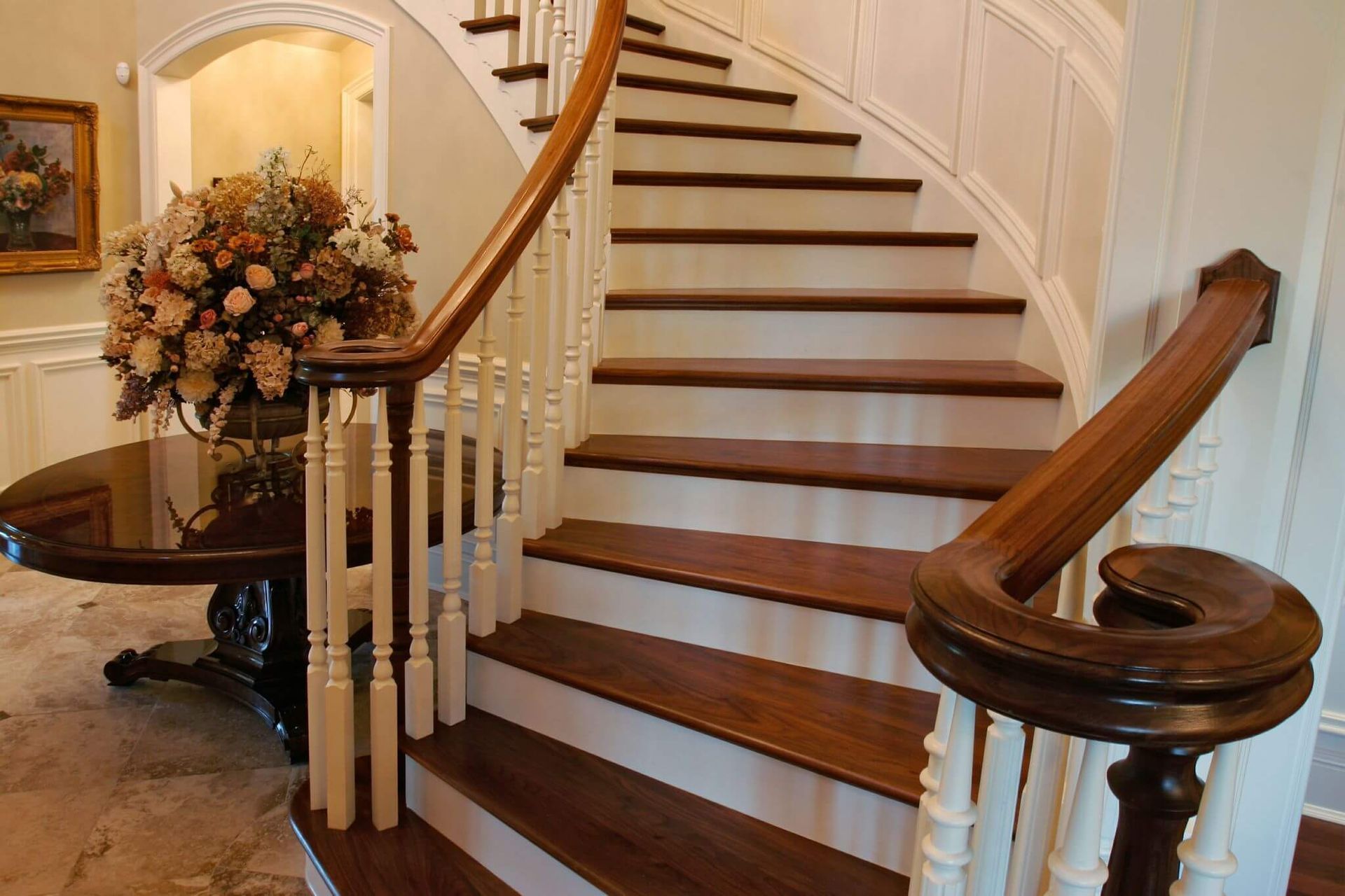 AD Construction NJ - Wooden curved staircase with white spindles, brown railing, and dark brown steps.