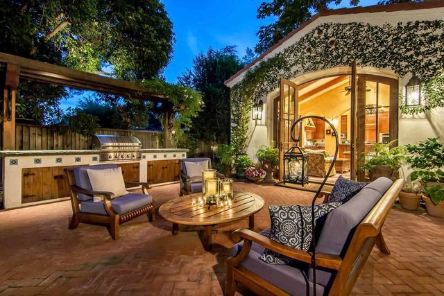 AD Construction NJ - Outdoor patio with furniture, grill, and open doors to a lit room.