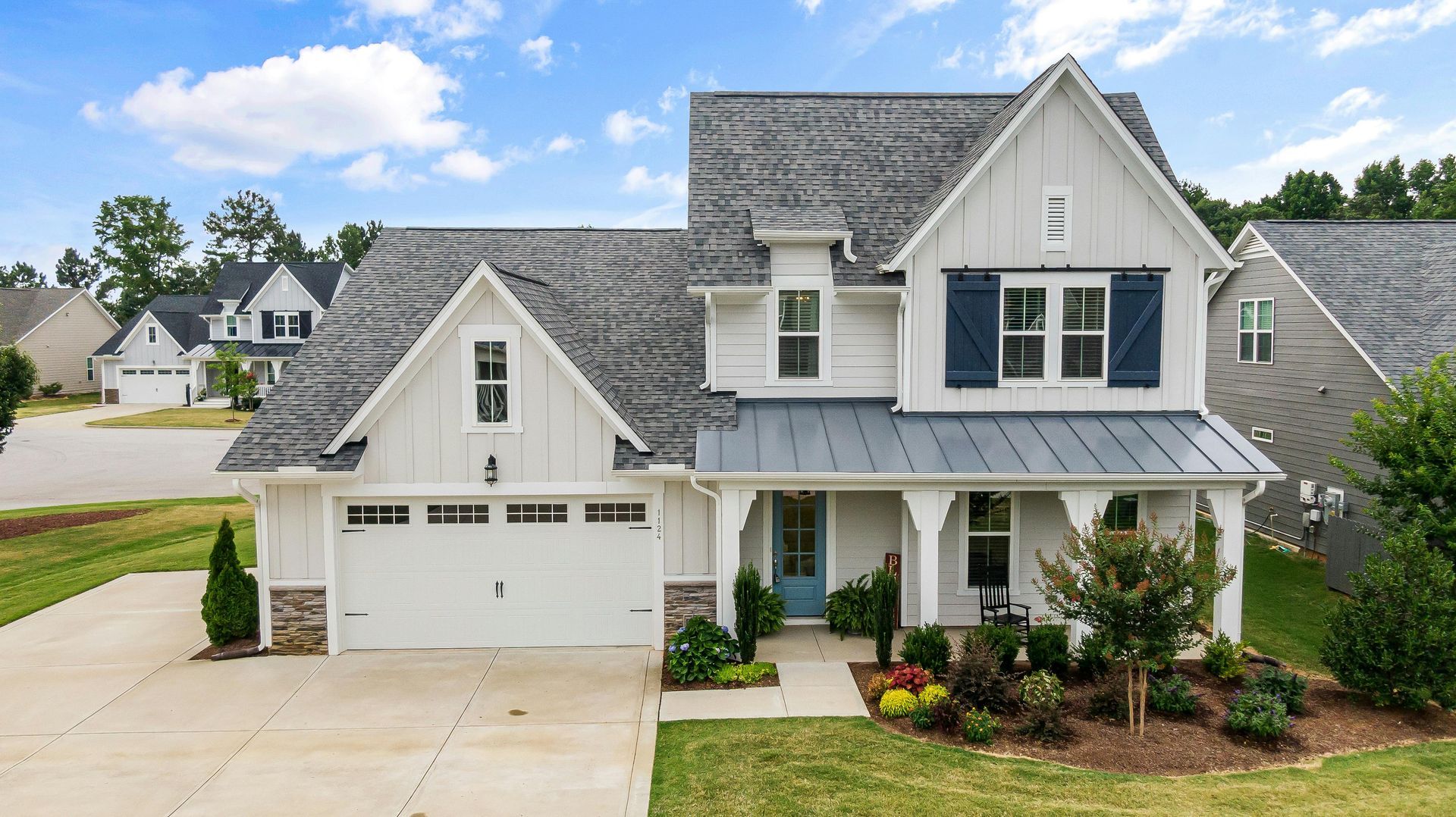 AD Construction NJ - White farmhouse with gray roof, blue shutters, and covered porch.