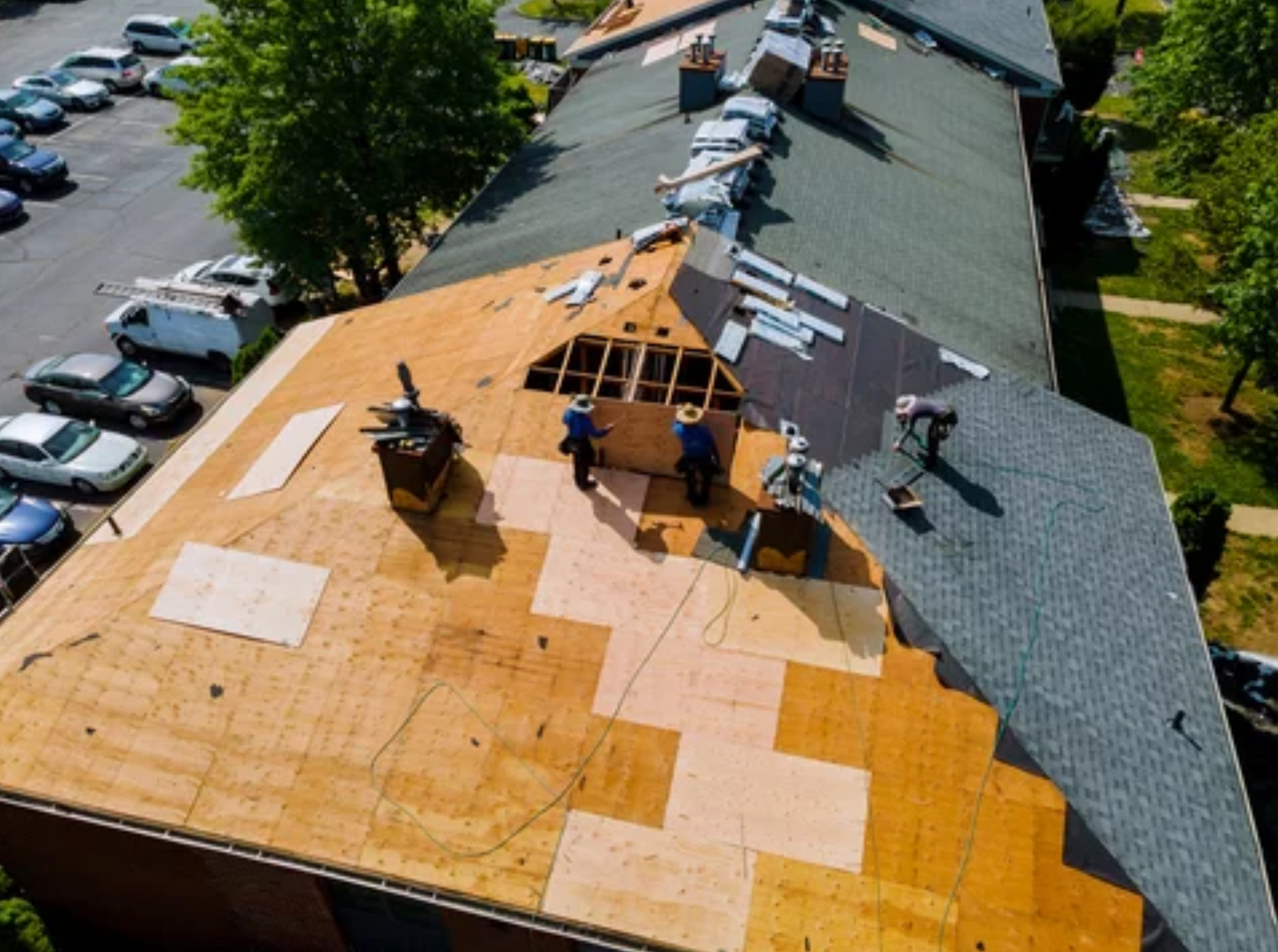 AD Construction NJ - Roofers working on a residential roof, wooden planks visible. Cars parked nearby.