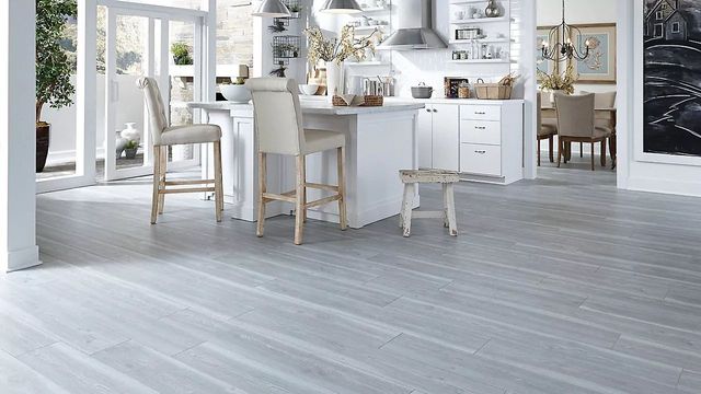 AD Construction NJ - Light gray wood flooring in a bright, modern kitchen with a white island and bar stools.