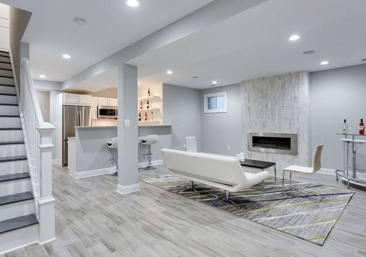 AD Construction NJ - Finished basement with a bar, fireplace, and seating area; gray and white color scheme.