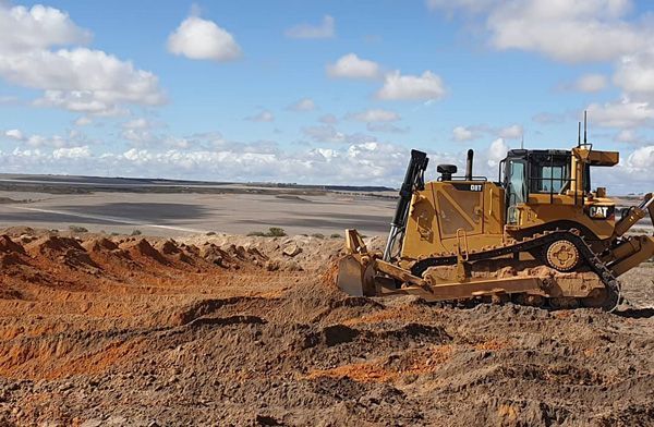 A bulldozer is driving through a dirt field.