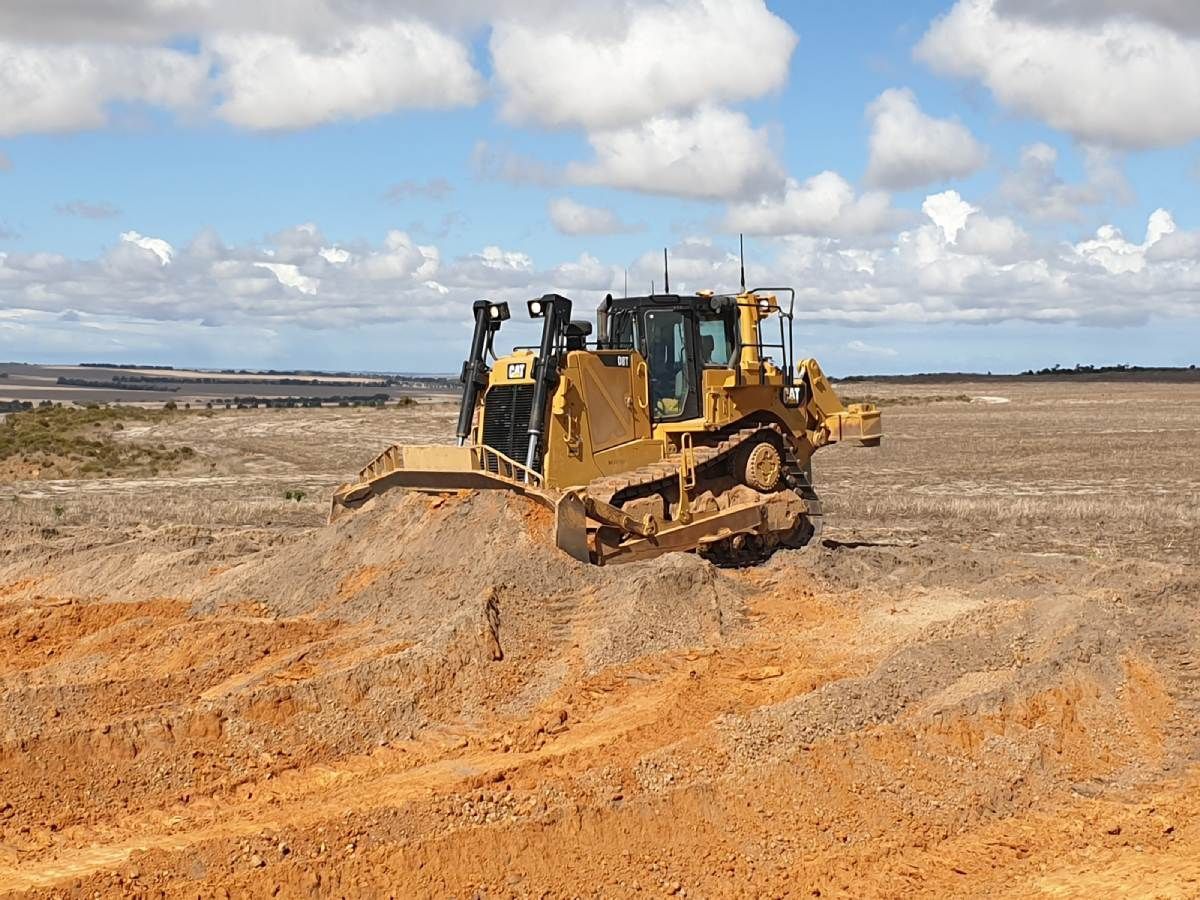 A bulldozer is driving through a dirt field.