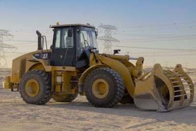 A bulldozer is parked in the middle of a dirt field.