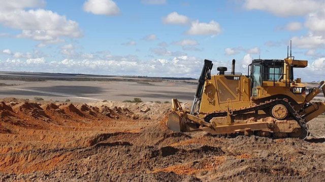 A bulldozer is moving dirt in a field.