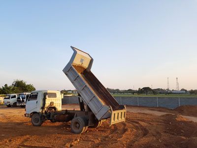 A dump truck is parked in a dirt lot with its bed open.