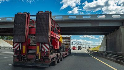 A semi truck is driving down a highway under a bridge.