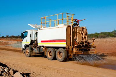 A truck is spraying water on a dirt road.