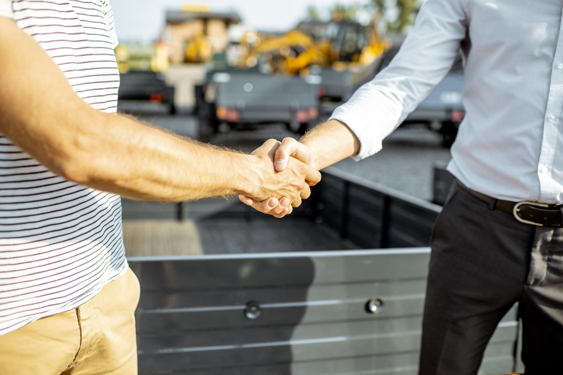 Two men are shaking hands in front of a truck.