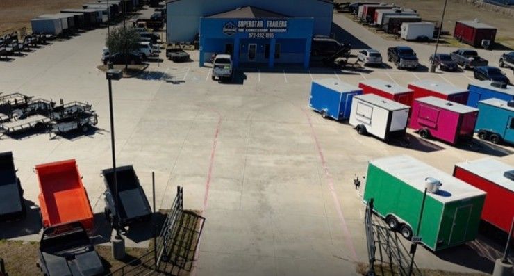 Black utility trailer with mesh gate, wooden bed, and black tires.