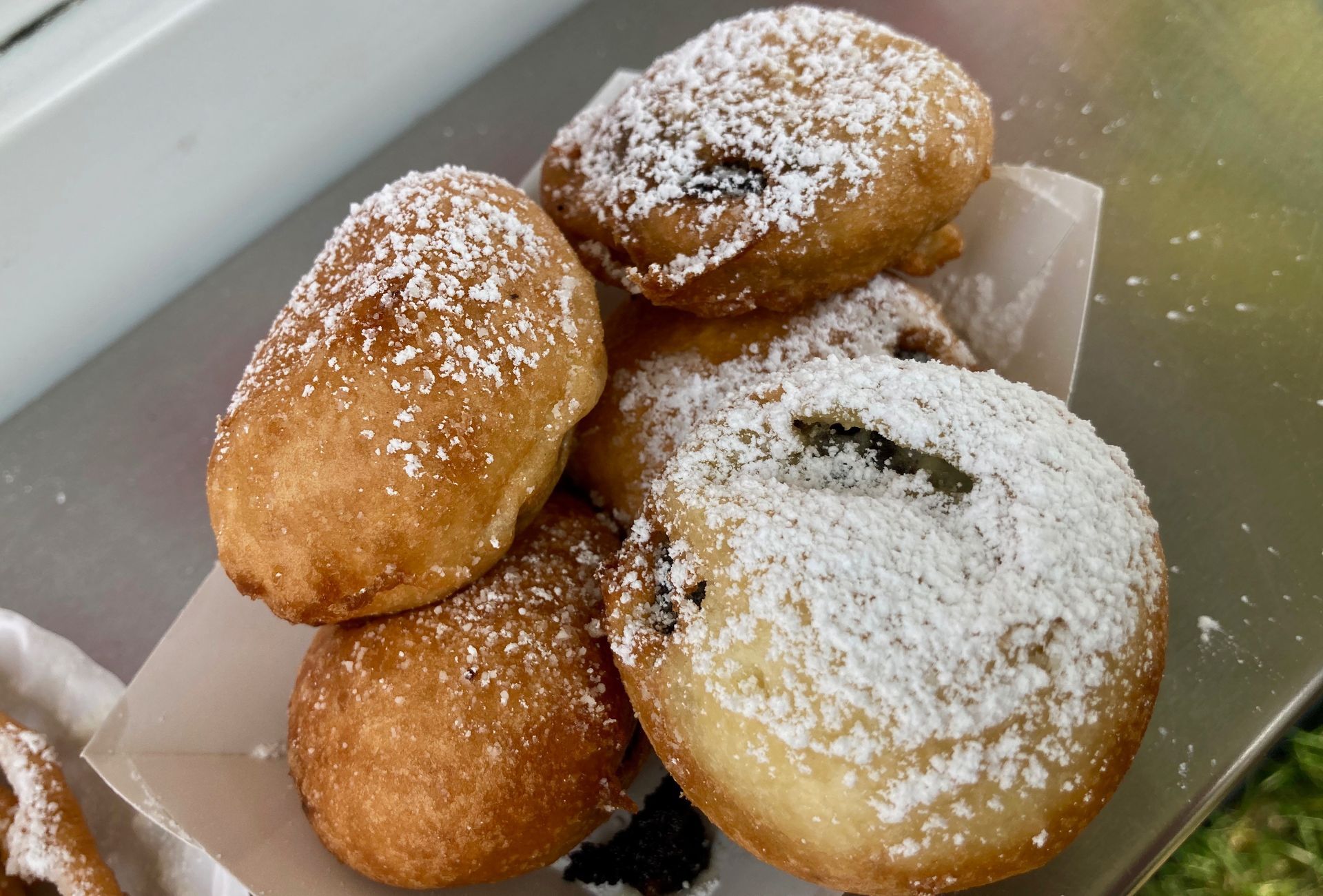 Fried dough balls with powdered sugar, piled on a small container.