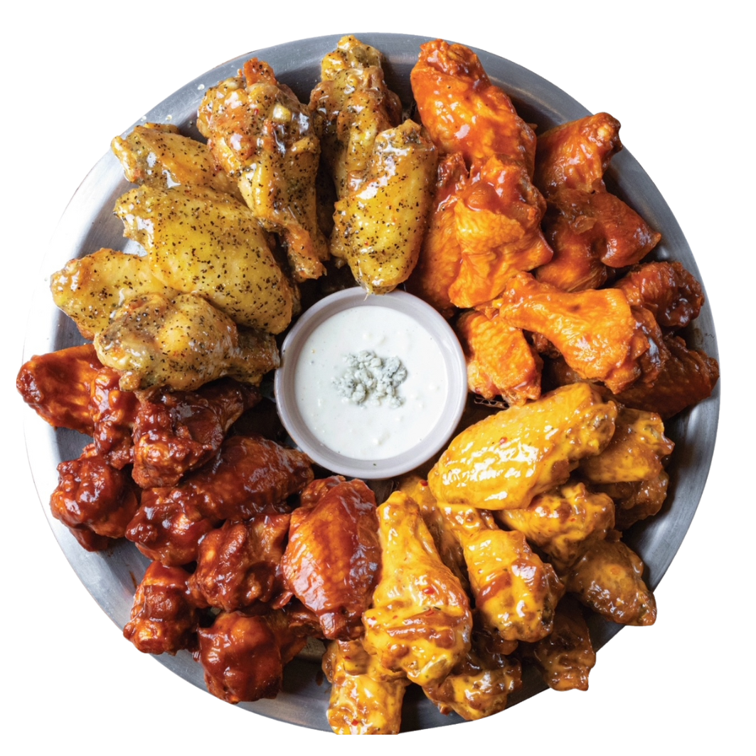 A platter of various chicken wings with dipping sauce in the center.