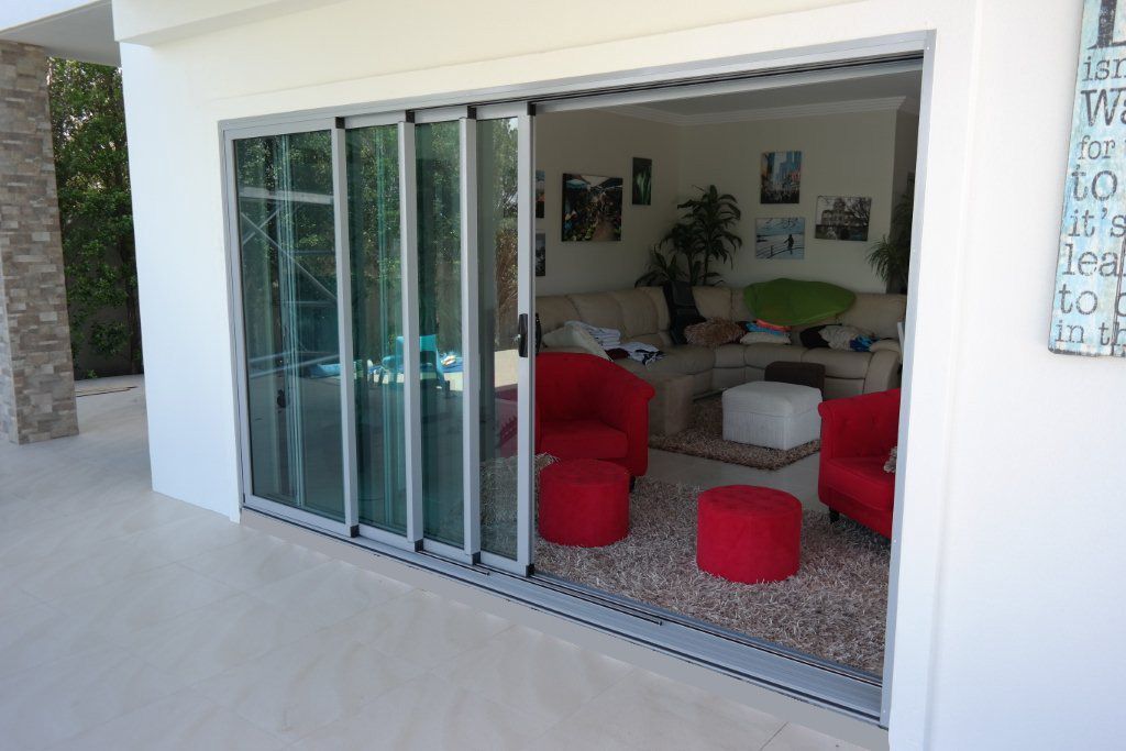 A Living Room With Sliding Glass Doors And Red Chairs — Datco Aluminium Pty Ltd In Murwillumbah, NSW