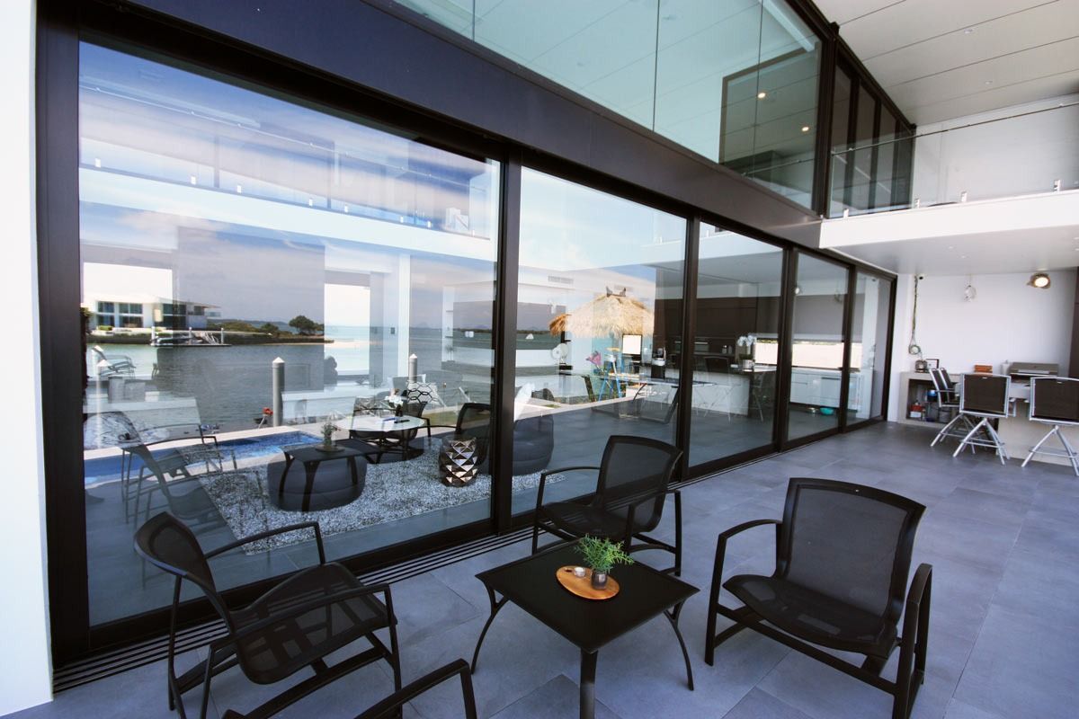 A Patio With Chairs And A Table In Front Of A Large Window — Datco Aluminium Pty Ltd In Murwillumbah, NSW