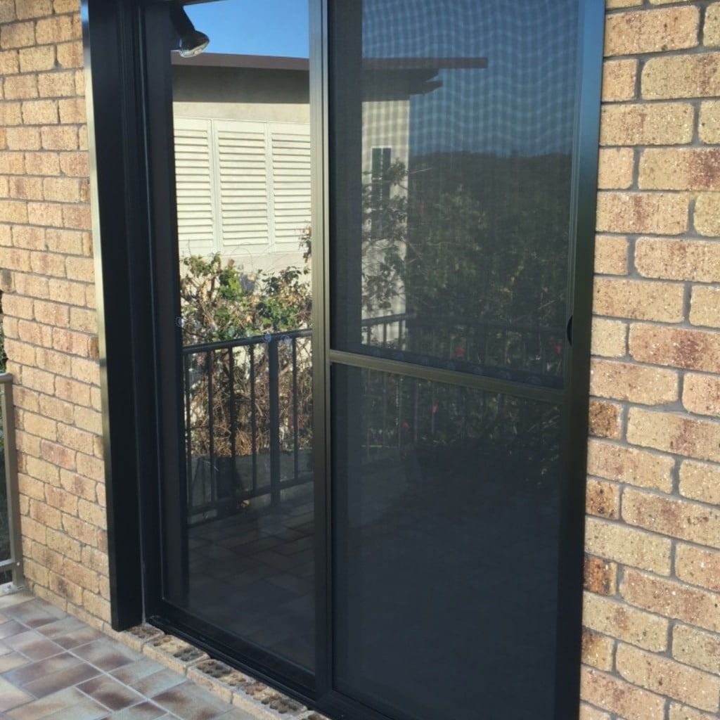 A Brick Building With A Black Sliding Glass Door — Datco Aluminium Pty Ltd In Murwillumbah, NSW