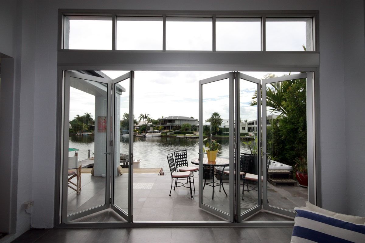 A Living Room With A View Of A Lake Through A Sliding Glass Door — Datco Aluminium Pty Ltd In Ballina, NSW