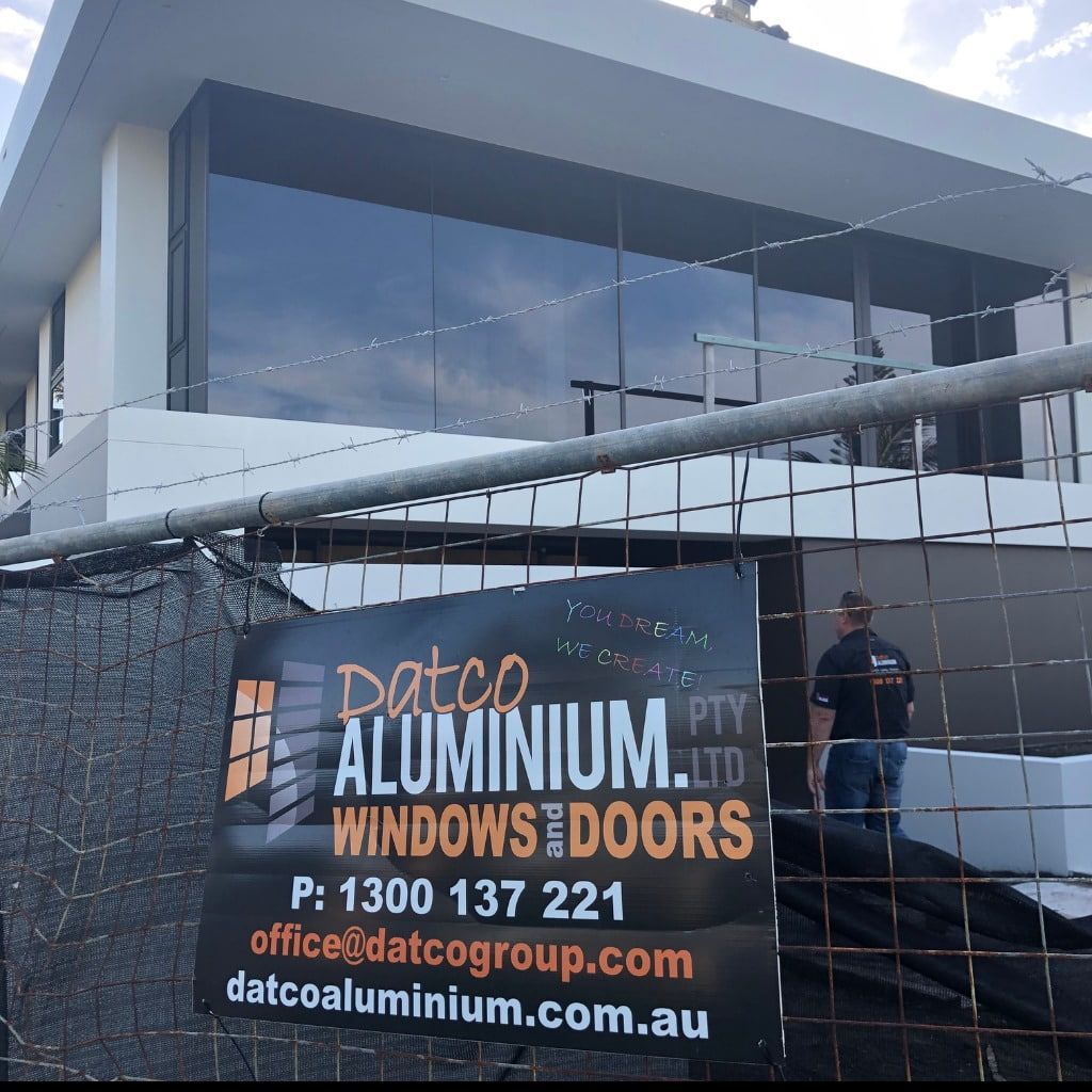 A Sign For Datco Aluminium Windows And Doors Is Behind A Fence — Datco Aluminium Pty Ltd In Ballina, NSW