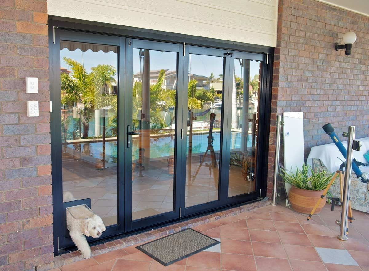 A Dog Is Looking Out Of A Sliding Glass Door — Datco Aluminium Pty Ltd In Murwillumbah, NSW