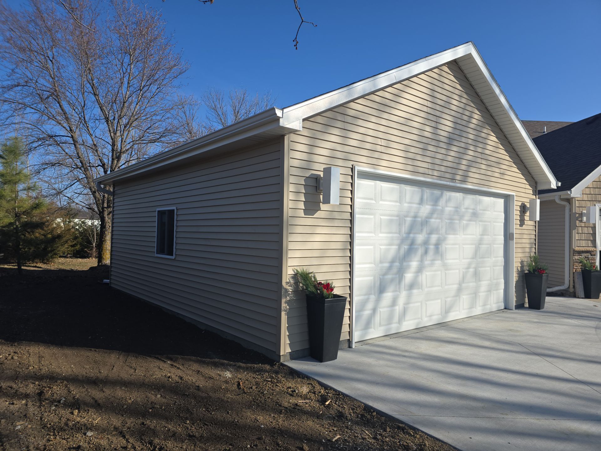 A garage with a white door is next to a house.