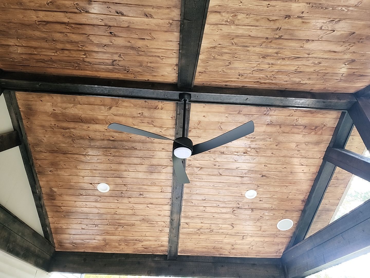 A wooden ceiling with a ceiling fan hanging from it.