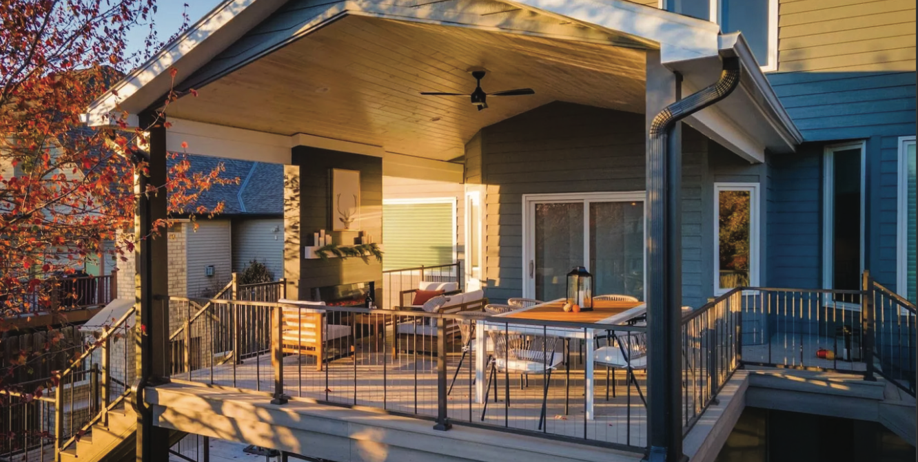 There is a large porch with a table and chairs on it.