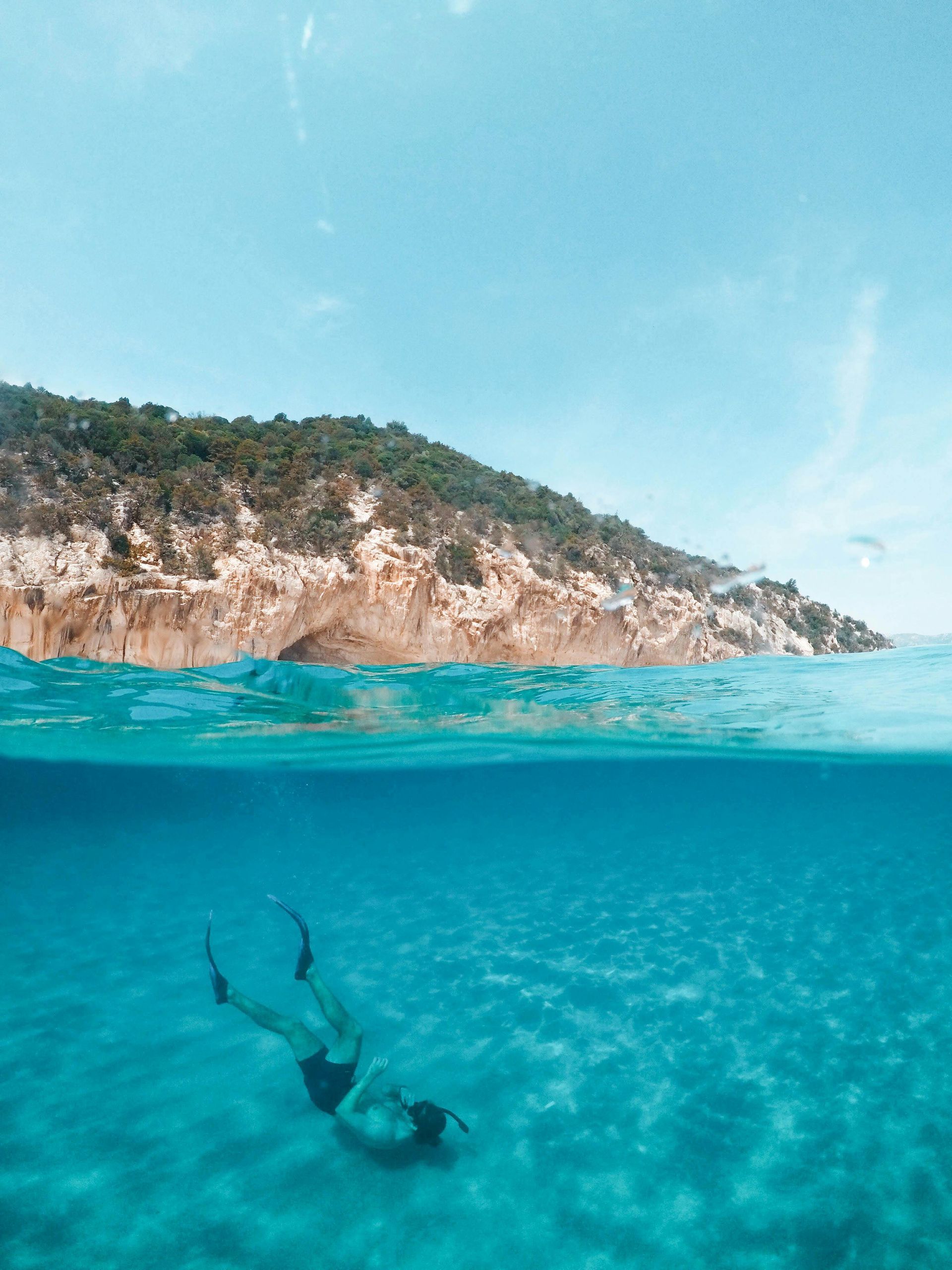 A woman is swimming in the ocean near a small island.
