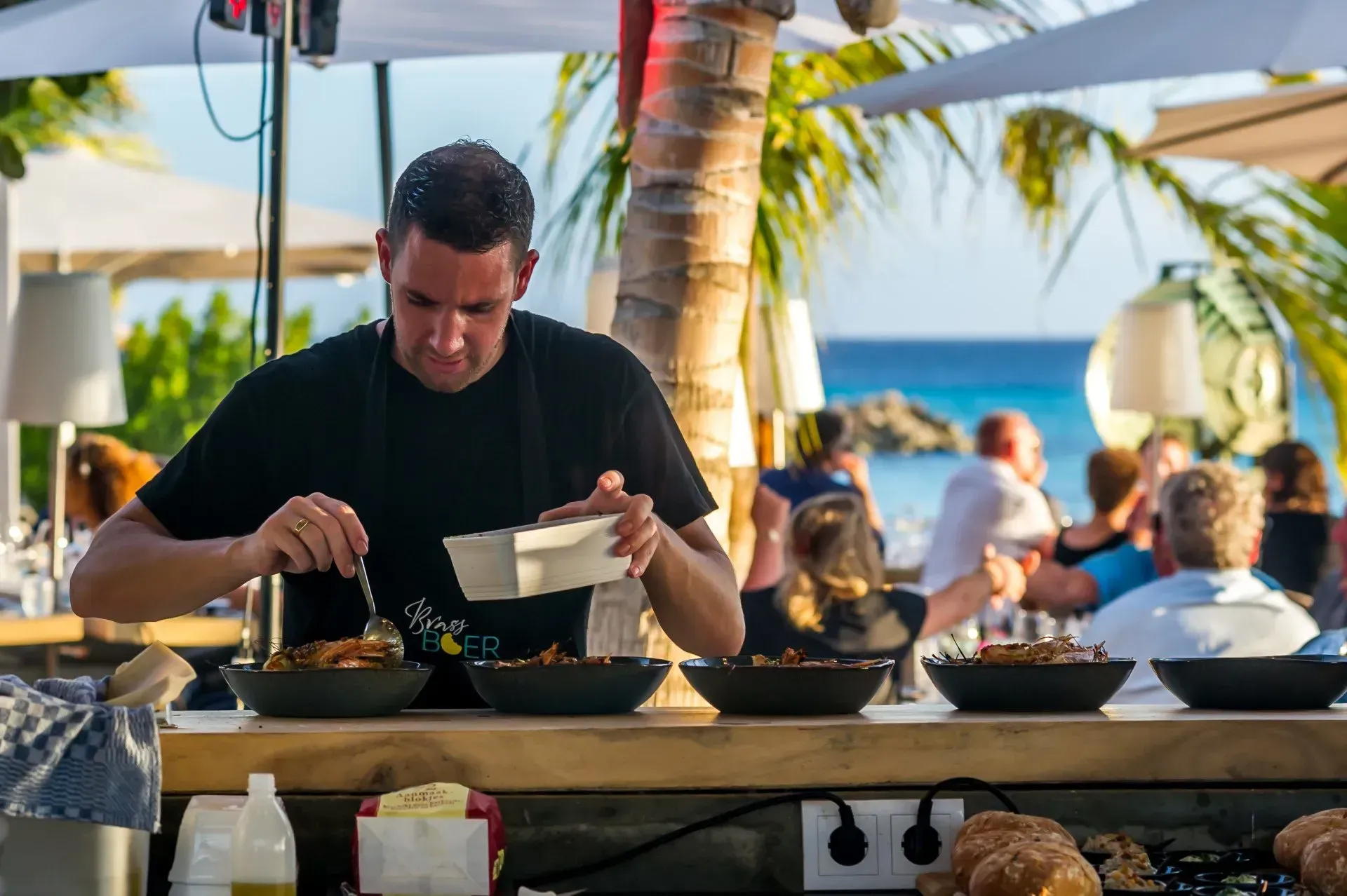 A man is preparing food at a restaurant on the beach.