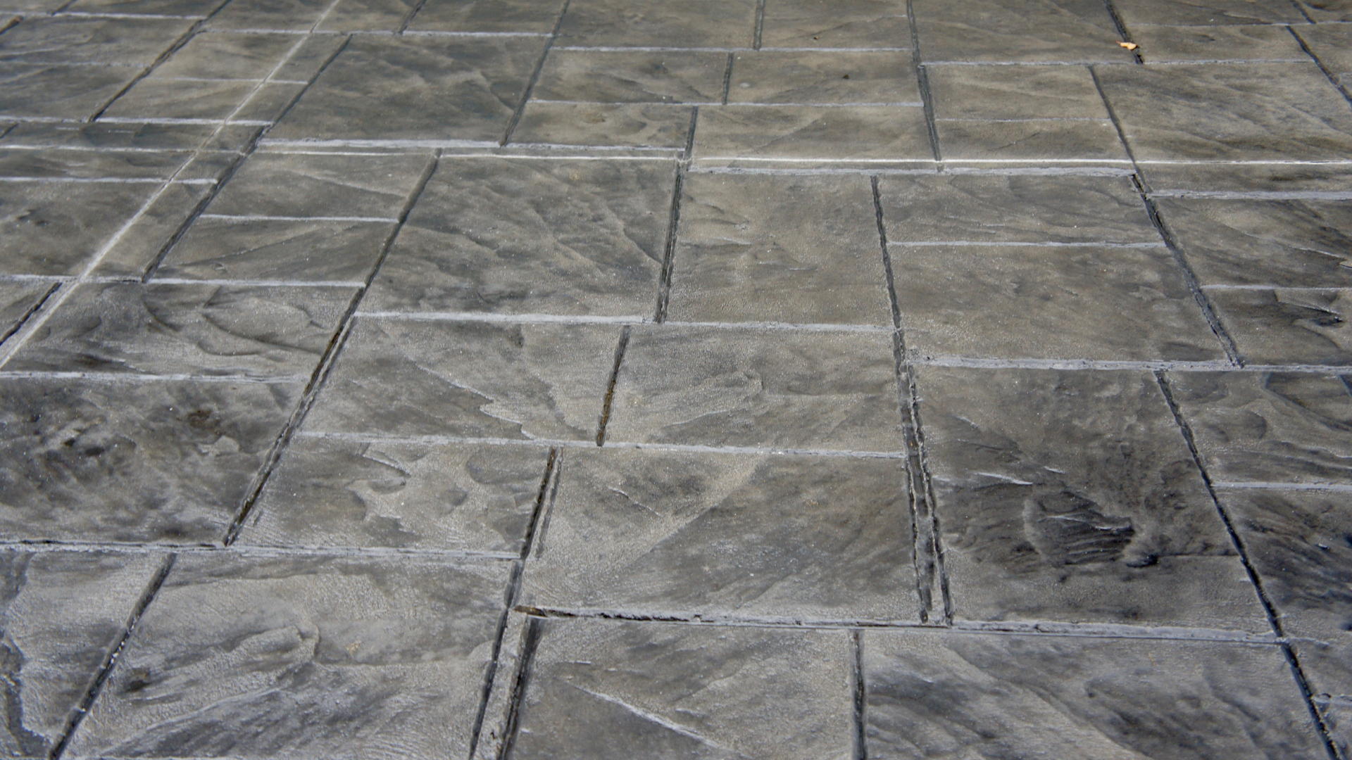 Textured gray concrete patio with rectangular and square tile pattern.