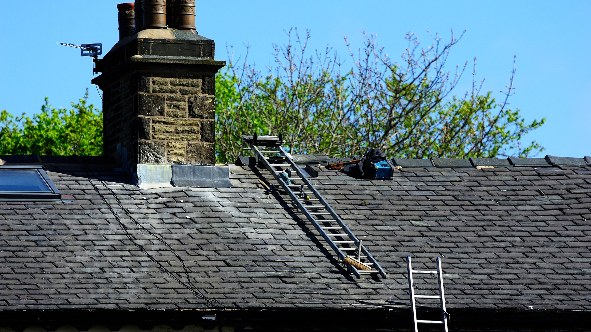 Ladder on a roof, leading to a chimney. Tools and a second ladder are also visible.