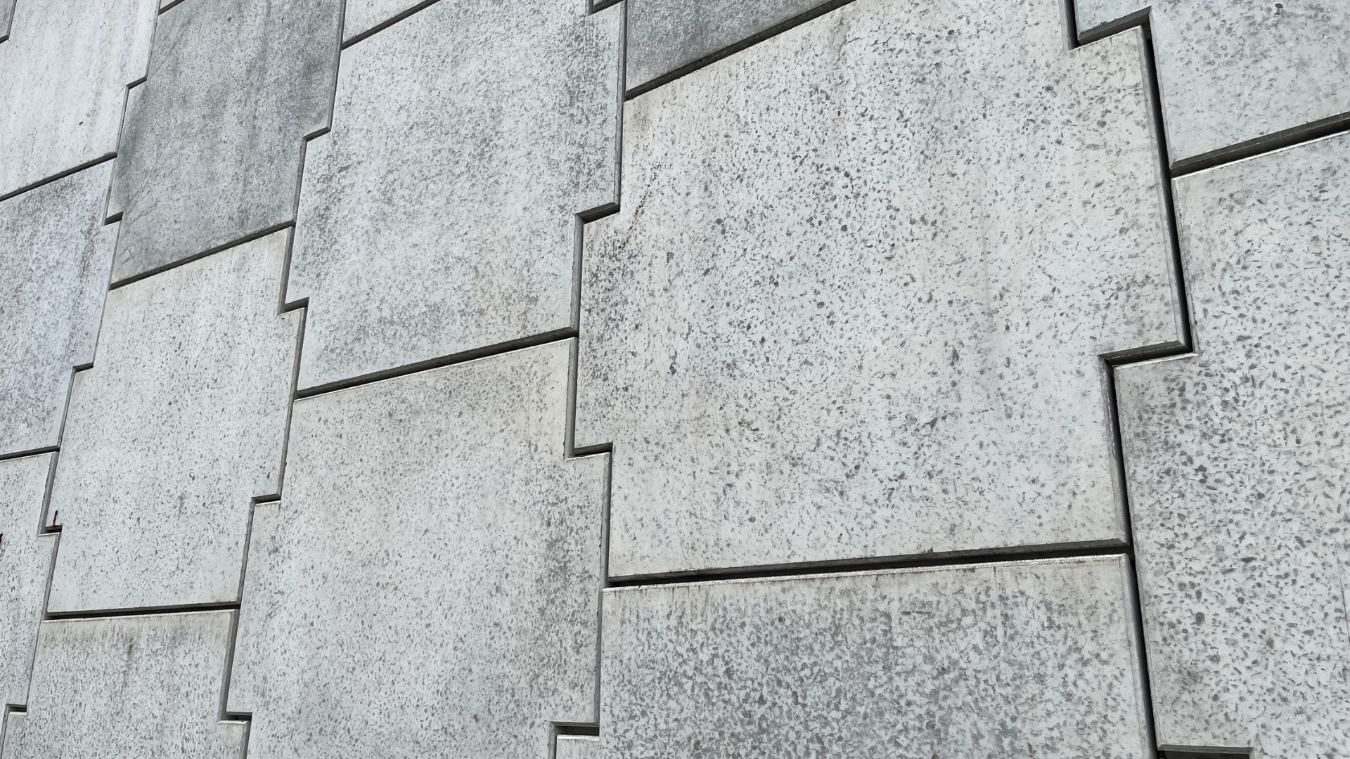Gray concrete wall composed of interlocking square tiles.