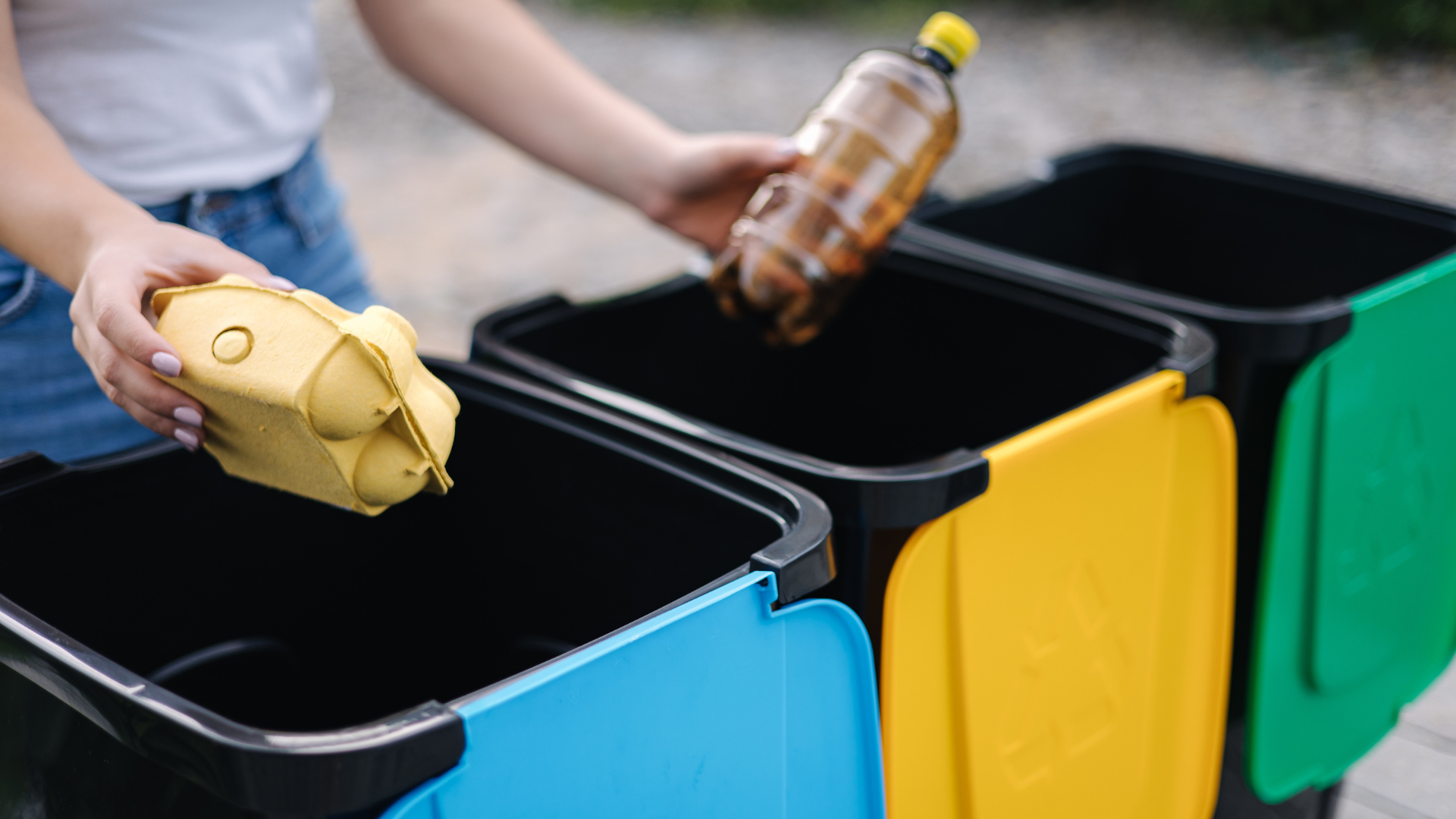a person is putting a plastic bottle into a yellow bin
