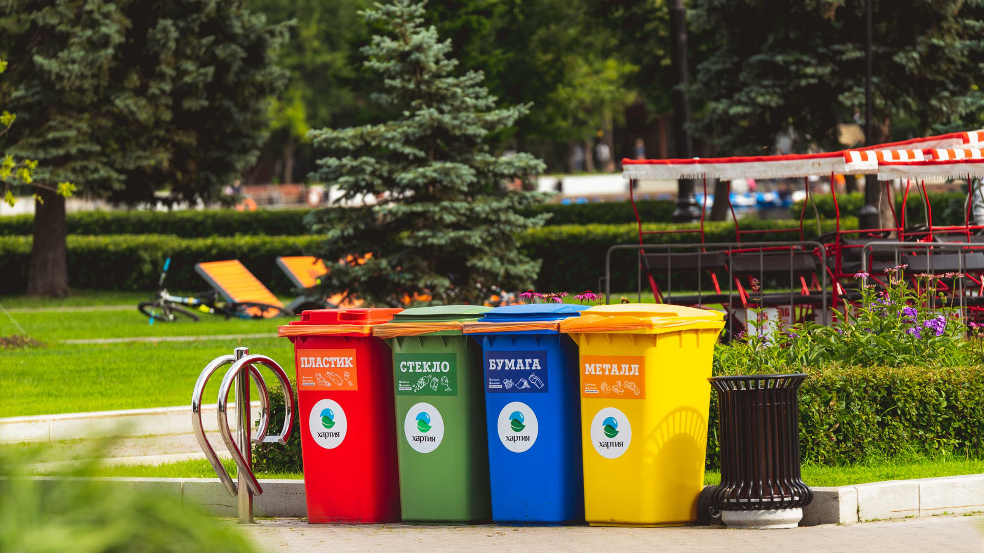 A row of colorful trash cans sitting next to each other in a park.