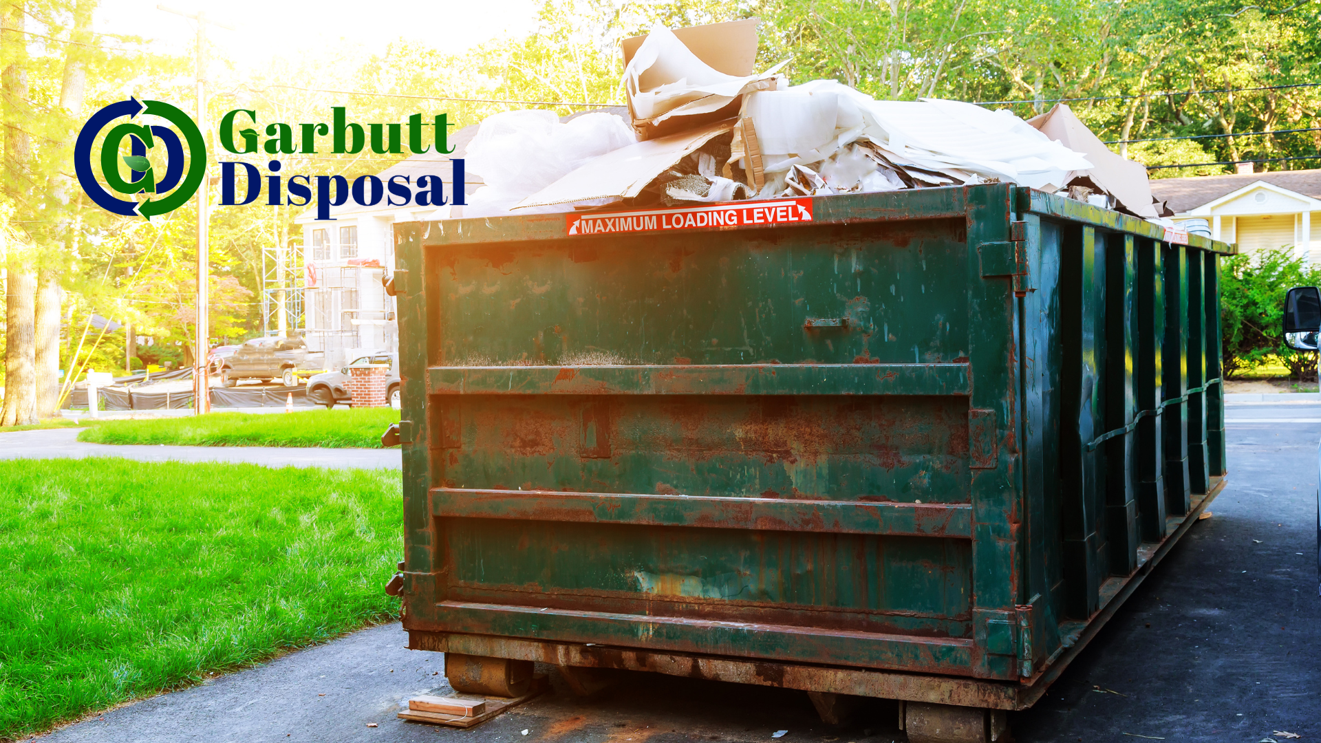 A large green dumpster is sitting on the side of a road.