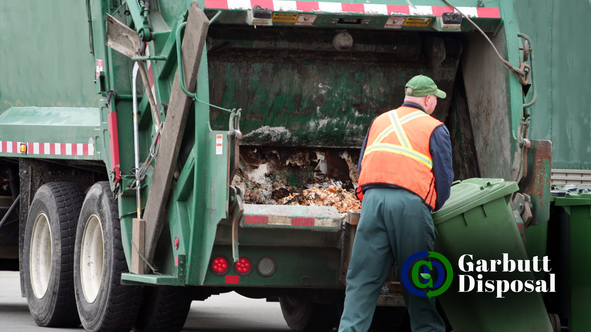 A garbage man is loading trash into a garbage truck.