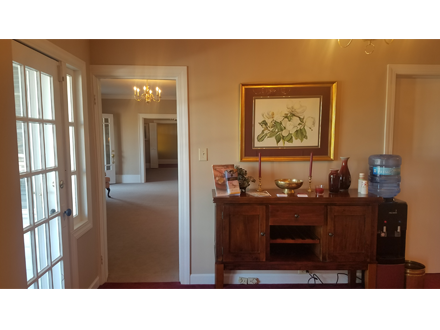 Interior view: entryway with French doors, hallway, wooden cabinet with artwork, water dispenser.