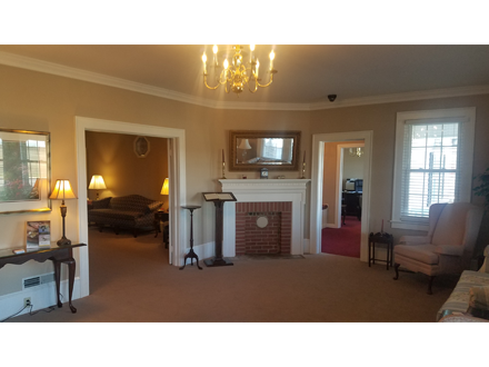 Interior of a tan-colored room with a fireplace, chandelier, and doorways leading to other rooms.