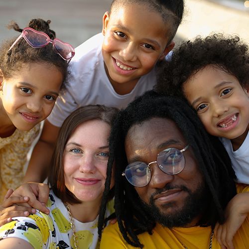 A group of children are posing for a picture with a man in a yellow shirt.