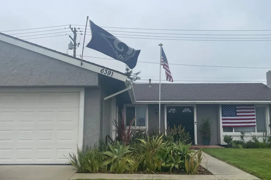 House with Rams and American flags; cloudy sky.